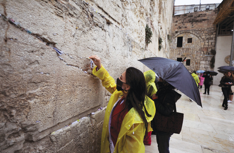  A MISS Universe contestant places a note in the Western Wall last year. The book describes how Jewish outreach activists often approach unaffiliated persons during visits to the site.  (photo credit: AMMAR AWAD/REUTERS)