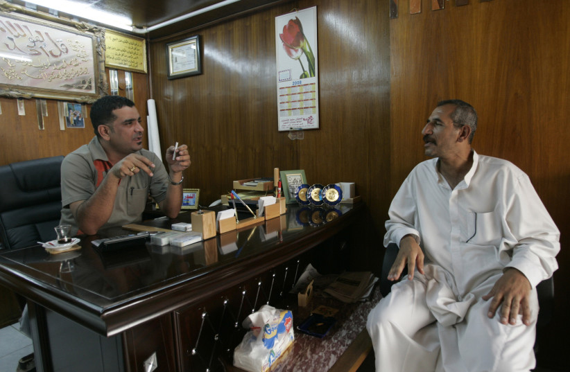 An agent talks to a client at a real estate office in Baghdad September 10, 2008. (photo credit: CEERWAN AZIZ/REUTERS)