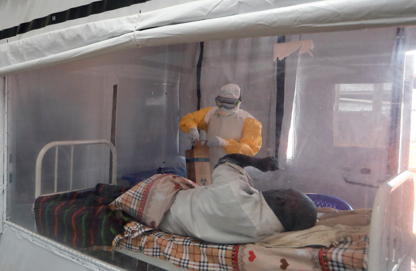 Nurse Moise Vaghemi tends to a patient who is suspected to be suffering from Ebola, inside the Biosecure Emergency Care Unit (CUBE) at an Ebola treatment centre (ETC) in Katwa, near Butembo, in the Democratic Republic of Congo, October 3, 2019. (photo credit: REUTERS/ZOHRA BENSEMRA)