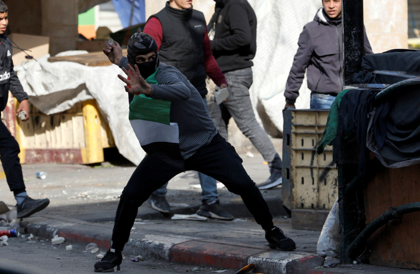  Demonstrators hurl stones at Israeli forces during a protest in solidarity with Palestinian prisoners held in Israeli jails, in Hebron in the Israeli-occupied West Bank February 18, 2022. (photo credit: REUTERS/MUSSA QAWASMA)