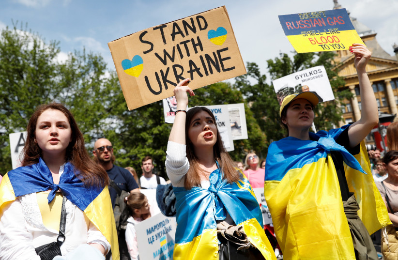 Women draped in Ukrainian flags hold up placards as they take part in a demonstration in support of Ukraine, amid Russia's invasion of the country, in Budapest, Hungary, April 30, 2022. (credit: REUTERS/BERNADETT SZABO)