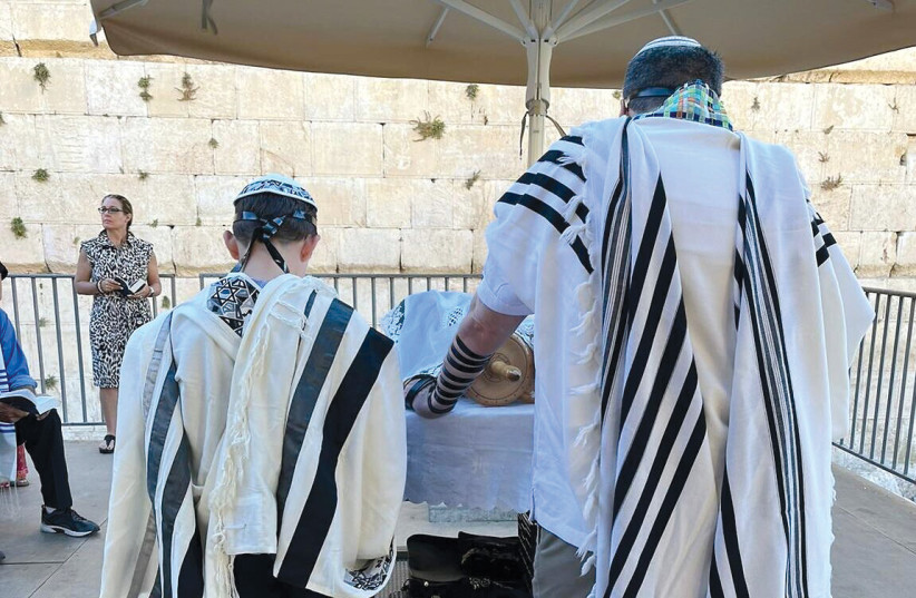  Seth Mann reads from a Torah scroll during his bar mitzvah ceremony at the Western Wall’s egalitarian section on June 30, 2022.  (photo credit: MANN FAMILY)