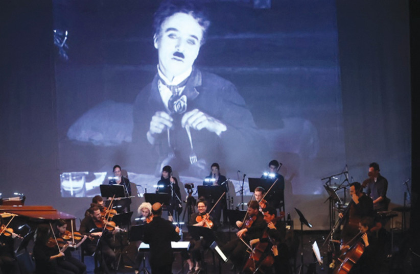  THE REVOLUTION Orchestra performs before a backdrop of Charlie Chaplin in his element. (photo credit: RAFI DELOUYA)