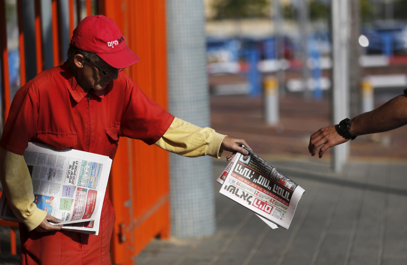  A man distributes the daily newspaper Israel Hayom at a train station in the southern city of Ashkelon, Israel November 19, 2015 (credit: AMIR COHEN/REUTERS)
