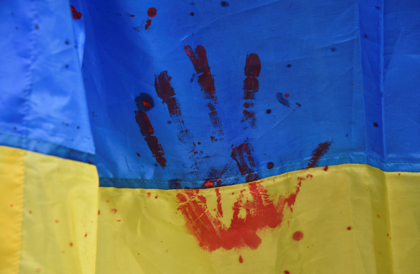  Participants hold Ukrainian national flag during a rally of relatives and friends of defenders of the Azovstal Iron and Steel Works in Mariupol, demanding to recognise Russia as a state sponsor of terrorism after killing Ukrainian prisoners of war (POWs) in a prison in Olenivka, outside of Donetsk. (photo credit: REUTERS/PAVLO PALAMARCHUK)