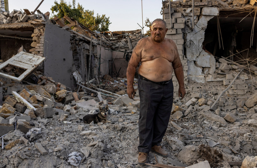  Alexander Shulga with his dog next to him reacts in front of his and his neighbour's home destroyed by a strike, amid Russia's invasion, in Mykolaiv, Ukraine, August 29, 2022.  (photo credit: REUTERS/UMIT BEKTAS)