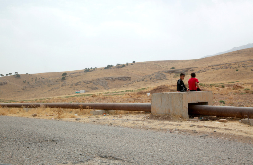  Boys sit on the Iraqi-Turkish pipeline in Zakho district of the Dohuk Governorate of the Iraqi Kurdistan province, Iraq, August 28, 2016. (credit: ARI JALAL / REUTERS)