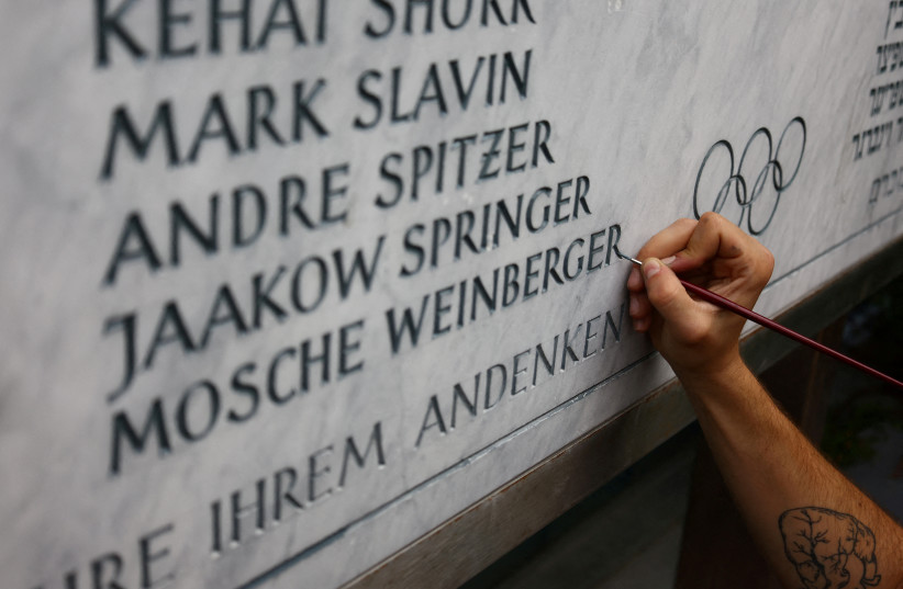  A stone cutter renovates a memorial stone for the 11 Israeli athletes killed by Palestinian terrorists during the 1972 Olympic Games, at the site of the hostage-taking at the former Olympic Village in Munich, Germany, August 18, 2022 (credit: REUTERS/WOLFGANG RATTAY)