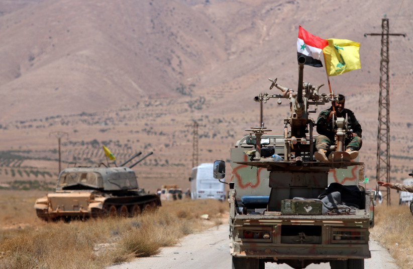 Hezbollah and Syrian flags flutter on a military vehicle in Western Qalamoun, Syria August 28, 2017.  (photo credit: REUTERS/OMAR SANADIKI)