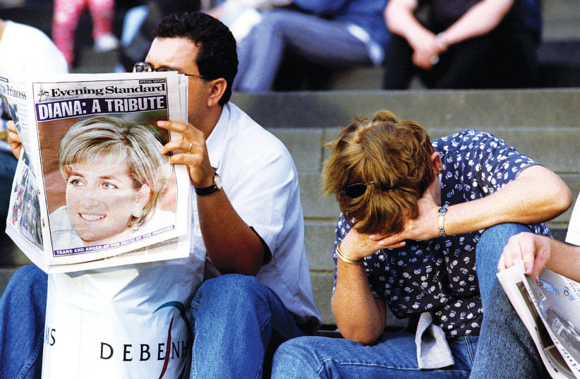  A MAN reads a paper paying tribute to Diana, Princess of Wales, as a woman covers her face in grief on the steps of St. Paul’s Cathedral in London, August 31, 1997. (photo credit: JASPER JUINEN/REUTERS )