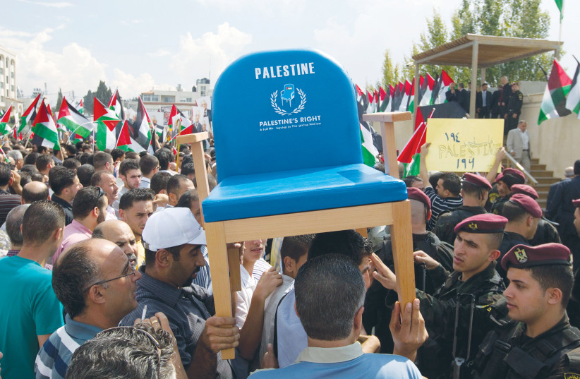  PALESTINIANS CARRY a chair representing their seat at the United Nations during a rally in Ramallah on Mahmoud Abbas’s return from the UN General Assembly after a bid for statehood in September 2011.  (credit: Darren Whiteside/Reuters)