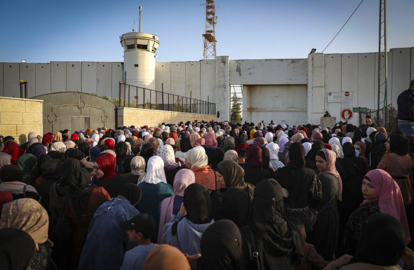  Israeli security forces guard as Palestinians make their way through an Israeli checkpoint to attend Friday prayer of the holy fasting month of Ramadan in Jerusalem's Al-Aqsa mosque, near the West Bank city of Bethlehem, April 29, 2022. (photo credit: WISAM HASHLAMOUN/FLASH90)