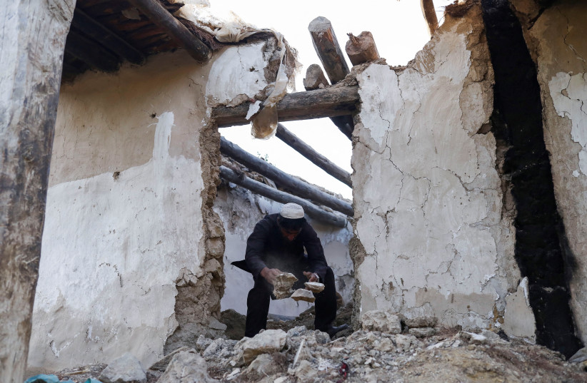 An Afghan man removes debris from his damaged house after the recent earthquake in Spolgin village in the Spera district of Khost province, Afghanistan, June 26, 2022. (photo credit:  REUTERS/ALI KHARA)