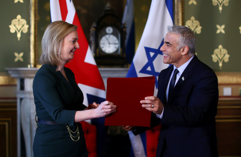  Britain's Foreign Secretary Liz Truss and Israeli Foreign Minister Yair Lapid exchange documents after signing a memorandum of understanding at Britain's Foreign Commonwealth & Development Office in London, Britain, November 29, 2021.  (credit: REUTERS/HANNAH MCKAY)