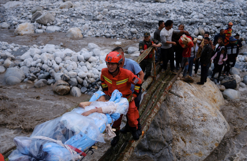 Rescue workers carry an injured victim on a stretcher following a 6.8-magnitude earthquake in Qinggangping village, Luding county, Ganzi Tibetan Autonomous Prefecture, Sichuan province, China September 5, 2022. (credit: CHINA DAILY VIA REUTERS)
