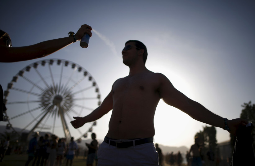  A man is sprayed with sunscreen at the Coachella Valley Music and Arts Festival in Indio, California April 11, 2015. (photo credit: REUTERS/LUCY NICHOLSON)