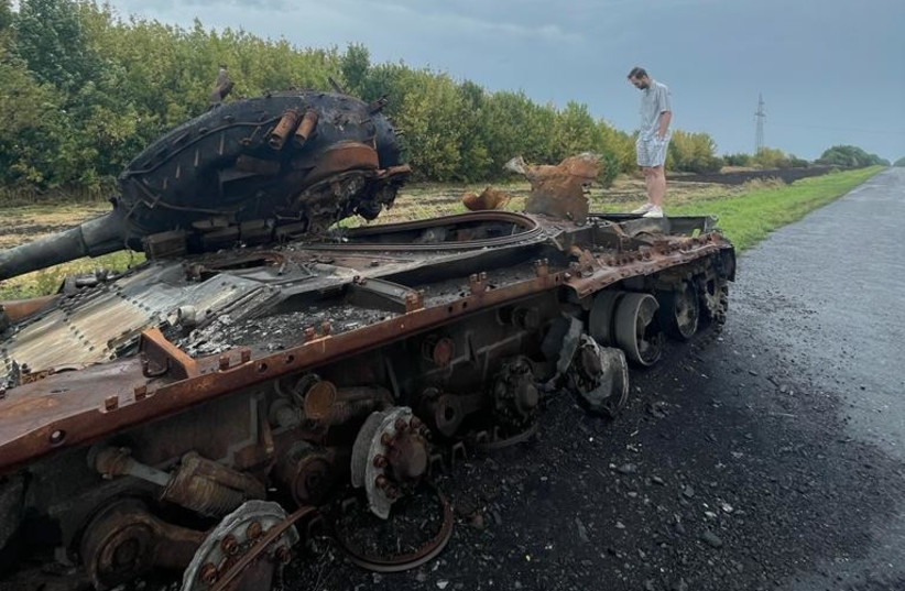  Biriuk Maksym standing on a destroyed Russian tank next to his farm in Rozsoshi, Ukraine, Aug. 30, 2022 (credit: Courtesy)