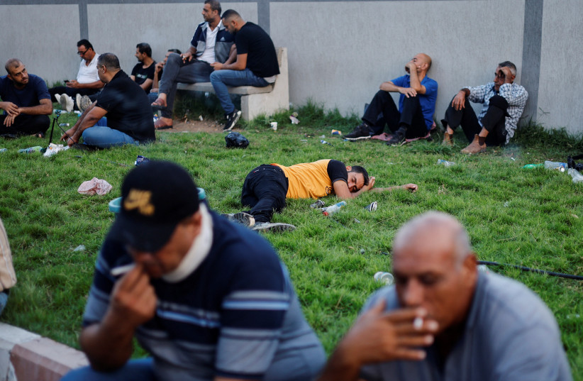  Palestinian workers rest as they wait to cross the Erez crossing to Israel in the northern Gaza Strip September 4, 2022. (credit: REUTERS/MOHAMMED SALEM)