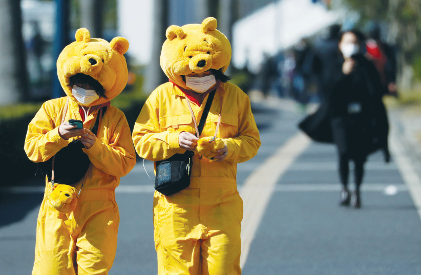  VISITORS WEARING face masks and Winnie-the-Pooh costumes are seen outside Tokyo Disneyland in  February 2020. The affable bear is being turned into a serial killer now that Disney no longer controls the rights. (photo credit: Issei Kato/Reuters)