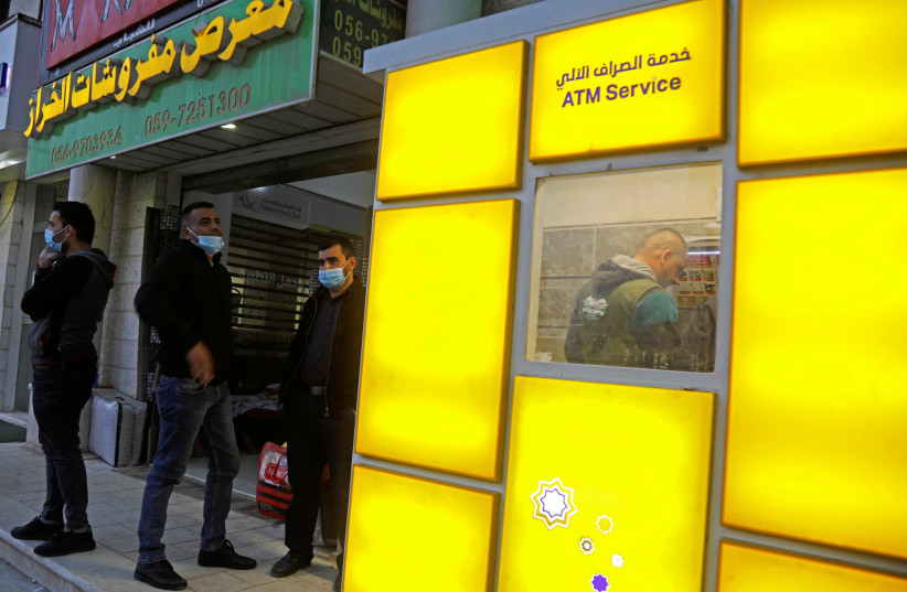  Palestinian Authority public servants wait to receive their salaries via an automated teller machine (ATM) outside a bank, in Tubas in the West Bank December 3, 2020.  (photo credit: REUTERS/RANEEN SAWAFTA)