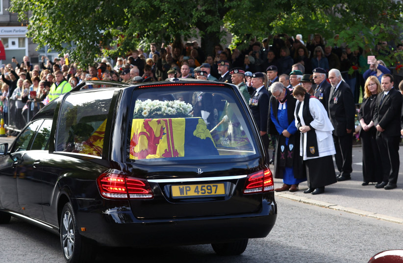  People line the street as the hearse carrying the coffin of Britain's Queen Elizabeth passes through the village of Ballater, near Balmoral, Scotland, Britain, September 11, 2022.  (photo credit: HANNAH MCKAY/ REUTERS)