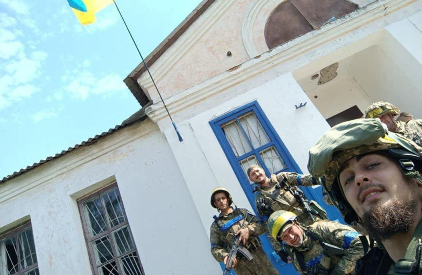  Service members pose for a picture with a Ukrainian national flag in the village of Vasylenkove, recently liberated by Ukrainian Armed Forces, amid Russia's attack on Ukraine, in Kharkiv region, Ukraine, in this handout picture released September 10, 2022. (photo credit: Press service of the Territorial Defence of the Ukrainian Armed Forces/Handout via REUTERS)