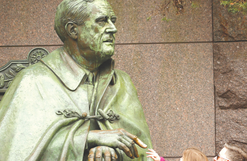  A CHILD is lifted up to touch fingertips with a statue of US president Franklin D. Roosevelt, in Washington. It is a fact that the Roosevelt administration’s track record on admitting Jewish refugees was worse than that of the Soviets and the British, says the writer (credit: KEVIN LAMARQUE/REUTERS)