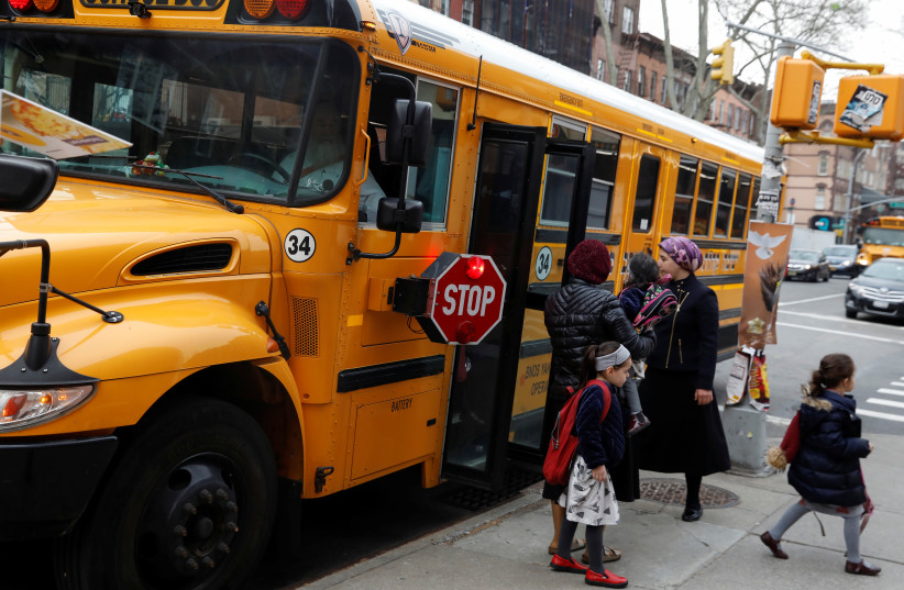 Orthodox Jewish children get off a Yeshiva school bus, as New York City Mayor Bill de Blasio declared a public health emergency in parts of Brooklyn in response to a measles outbreak, in the Williamsburg neighborhood of Brooklyn in New York City, US, April 9, 2019. (photo credit: REUTERS/SHANNON STAPLETON)