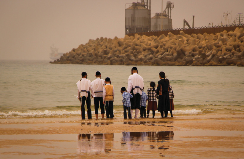  A HAREDI family walks on the beach in Ashdod this past Passover (Illustrative) (photo credit: GERSHON ELINSON/FLASH90)