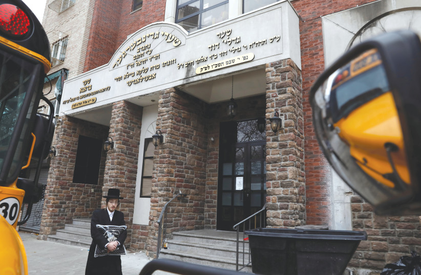  AN ORTHODOX man walks by the Yeshiva Kehilath Yakov school in Brooklyn. (credit: Shannon Stapleton/Reuters)