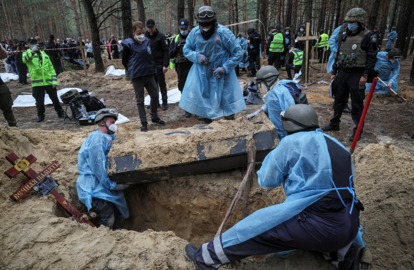 Members of Ukrainian Emergency Service, police and experts work at a place of mass burial during an exhumation, as Russia's attack on Ukraine continues, in the town of Izium, recently liberated by Ukrainian Armed Forces, in Kharkiv region, Ukraine, September 16, 2022. (photo credit: REUTERS/GLEB GARANICH)