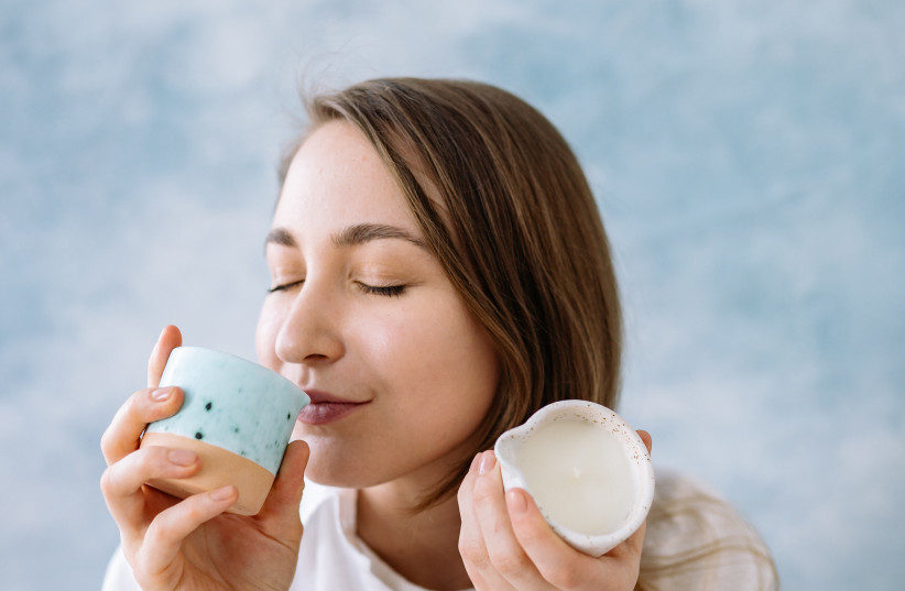  Woman smells scented candle (Illustrative) (photo credit: PEXELS)