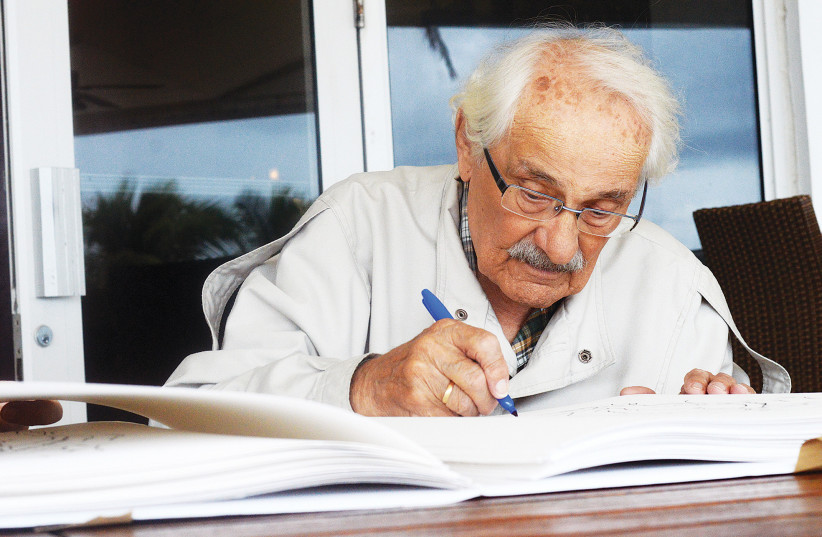  Samuel Willenberg, one of the leaders of the Treblinka revolt, signs sketches of one of his sculptures of scenes at Treblinka, 2014 (photo credit: Zachary Fagenson/Reuters)