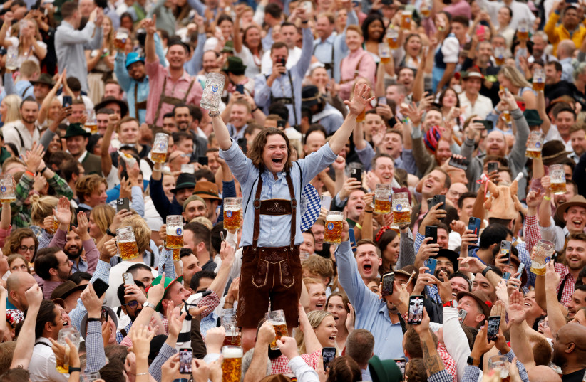 A visitor cheers after finishing a mug of beer during the official opening the world's largest beer festival, the 187th Oktoberfest in Munich, Germany, September 17, 2022. (photo credit: REUTERS/MICHAELA REHLE)