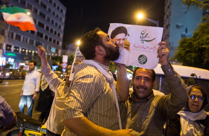 Un partisan du candidat présidentiel iranien Ebrahim Raisi embrasse son affiche lors d'un rassemblement électoral à Téhéran, Iran, le 17 mai 2017. (Crédit : TIMA VIA REUTERS)