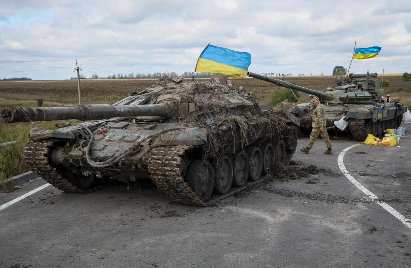 A Ukrainian serviceman walks near captured Russian tanks with installed Ukrainian flags, as Russia's attack on Ukraine continues, near the town of Izium, recently liberated by Ukrainian Armed Forces, in Kharkiv region, Ukraine, September 19, 2022. (photo credit: REUTERS/GLEB GARANICH)