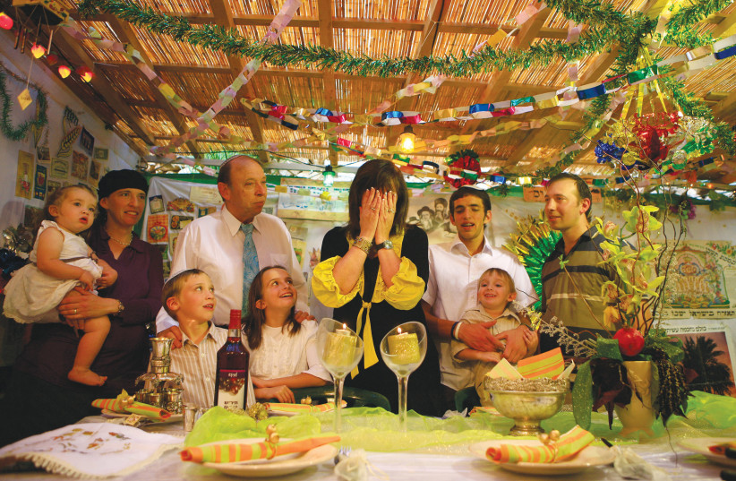  A FAMILY brings in the Sukkot holiday with candle lighting, and the table in the sukkah is set for the festive meal (photo credit: YOSSI ALONI/FLASH90)