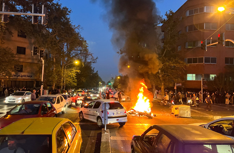 A police motorcycle burns during a protest over the death of Mahsa Amini, a woman who died after being arrested by the Islamic republic's "morality police", in Tehran, Iran, September 19, 2022. (photo credit: WANA (WEST ASIA NEWS AGENCY) VIA REUTERS)