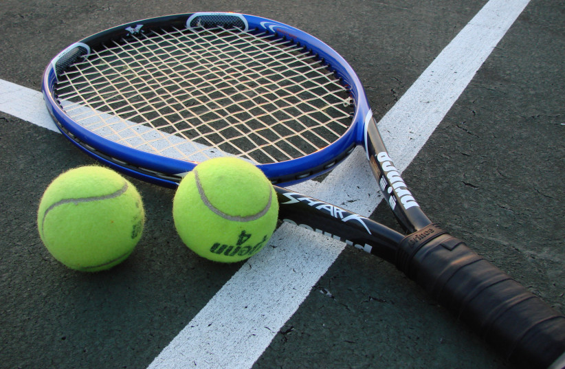 A tennis racket and two tennis balls on a court (photo credit: VLADSINGER/CC BY-SA 3.0 (http://creativecommons.org/licenses/by-sa/3.0/)/VIA WIKIMEDIA COMMONS)