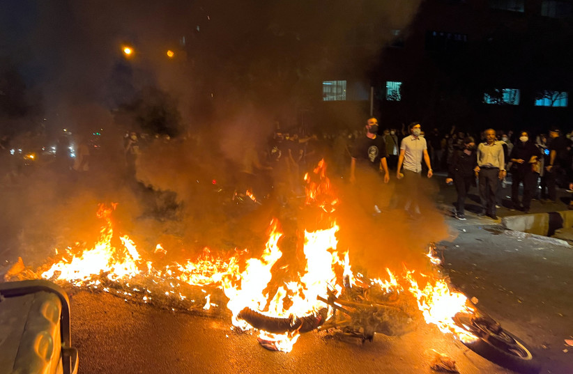 A police motorcycle burns during a protest over the death of Mahsa Amini, a woman who died after being arrested by the Islamic republic's "morality police", in Tehran, Iran September 19, 2022. (photo credit: WANA (WEST ASIA NEWS AGENCY) VIA REUTERS)