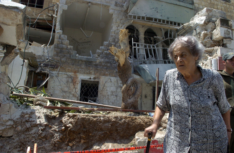  An old Israeli woman walks in front of a building destroyed by a Katyusha rocket in the town of Haifa on August Monday 07.2006 (credit: Max Yelinson/Flash90)