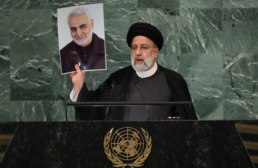  Iran's President Ebrahim Raisi holds up a picture of Quds Force Commander General Qassem Soleimani, who was killed in a U.S. attack, as he addresses the 77th Session of the United Nations General Assembly at U.N. Headquarters in New York City, U.S., September 21, 2022. (photo credit: BRENDAN MCDERMID/REUTERS)