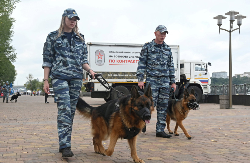  Police officers patrol with dogs next to a mobile recruitment center for military service under contract in Rostov-on-Don, Russia September 17, 2022.  (credit: SERGEY PIVOVAROV/REUTERS)