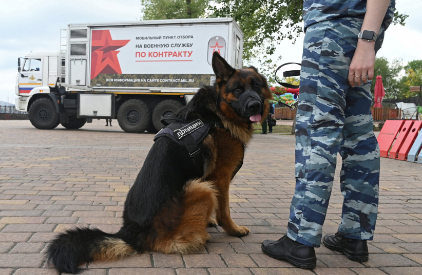  A female police officer stands with a dog next to a mobile recruitment center for military service under contract in Rostov-on-Don, Russia September 17, 2022.  (photo credit: SERGEY PIVOVAROV/REUTERS)