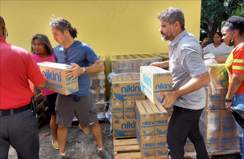  Jeff Berezdivin, left, and Diego Mandelbaum, right, of San Juan's Congregation Shaare Zedek distribute pallets of bottled water to flooded residents of Loiza devastated by Hurricane Fiona. (photo credit: Courtesy of Diego Mandelbaum / VIA JTA)