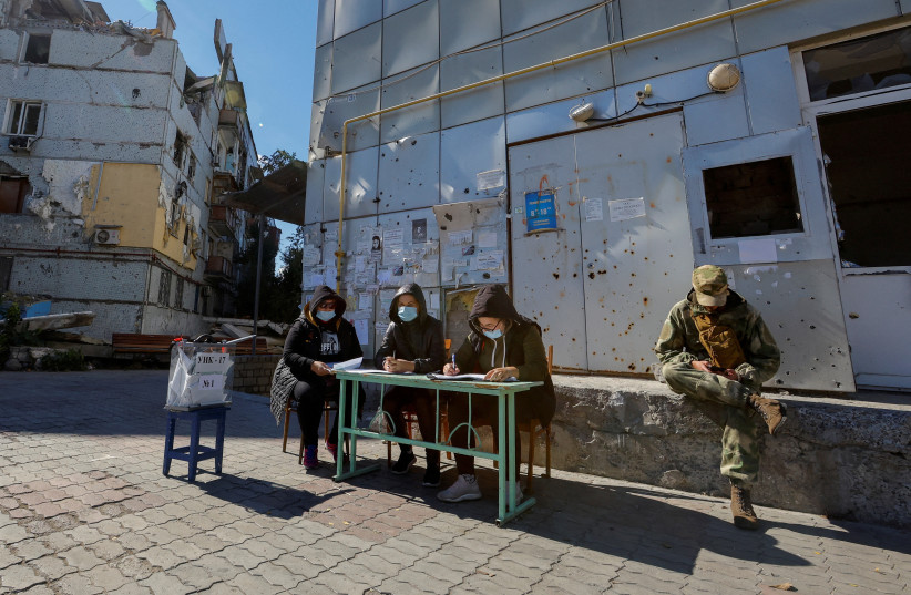  Members of an electoral commission wait for voters near a destroyed residential building on the third day of a referendum on the joining of the self-proclaimed Donetsk People's Republic (DPR) to Russia, in Mariupol, Ukraine (photo credit: REUTERS)