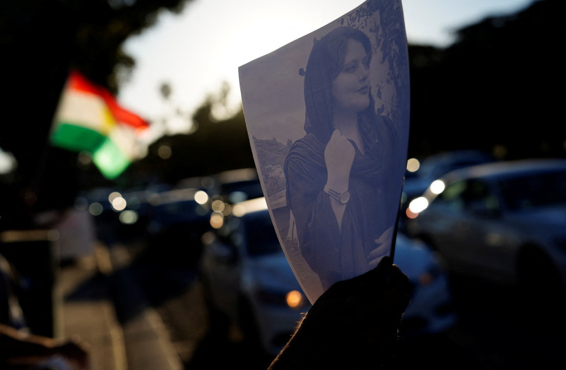  A demonstrator displays an image of Iranian Kurdish woman Mahsa (Zhina) Amini, at a protest following her death, outside the Wilshire Federal Building in Los Angeles, California, US, September 22, 2022 (photo credit: REUTERS/BING GUAN)