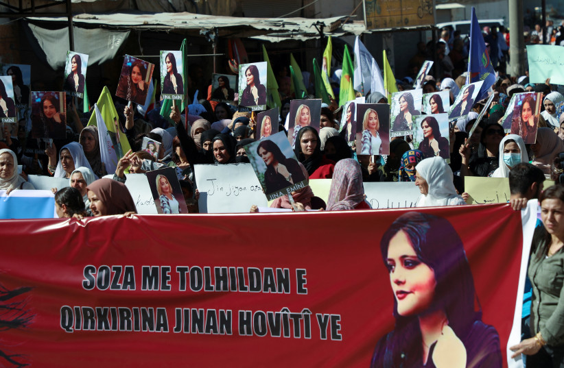  Women carry banners and pictures during a protest following the death of 22-year-old Kurdish woman Mahsa Amini in Iran, in the Kurdish-controlled city of Qamishli, northern Syria September 26, 2022 (photo credit: REUTERS/Orhan Qereman)
