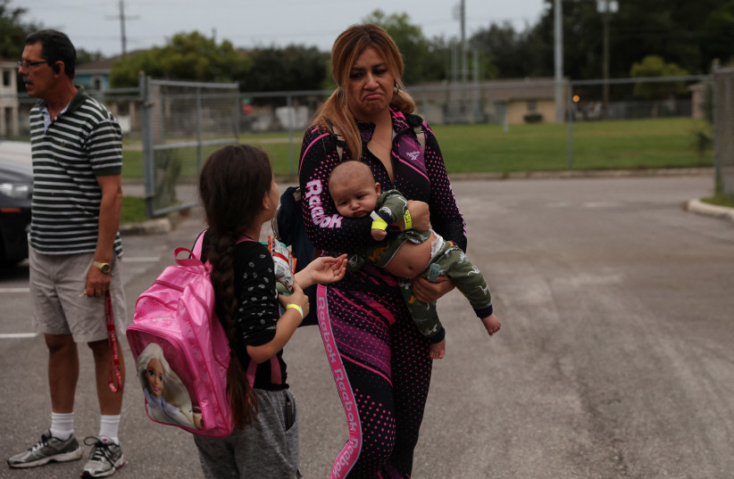  A woman holding a baby enters a shelter for evacuees, as Hurricane Ian spun towards the state carrying high winds, torrential rains and a powerful storm surge, with a child at Lockhart Elementary school in Tampa, Florida, US, September 27, 2022.  (credit: SHANNON STAPLETON/ REUTERS)
