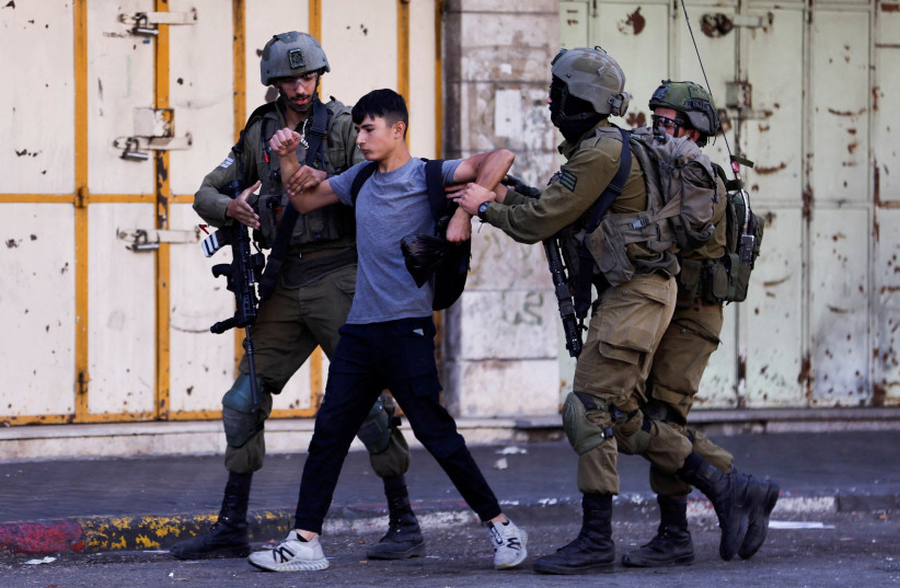  Israeli troops detain a man during a Palestinian protest over the killing of Palestinian gunmen in an Israeli raid on Wednesday, in Hebron in the Israeli-occupied West Bank September 29, 2022 (credit: MUSSA QAWASMA/REUTERS)